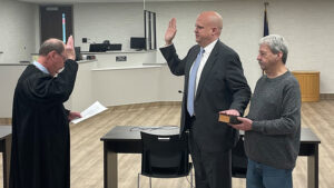 Thomas A. Cannon Jr., Judge of the Delaware Circuit Court No. 5 is pictured administering the Oath of Office to Eric Hoffman. Eric’s father, Charles Hoffman is holding the bible during the swearing-in ceremony. Photo courtesy of MuncieJournal.com